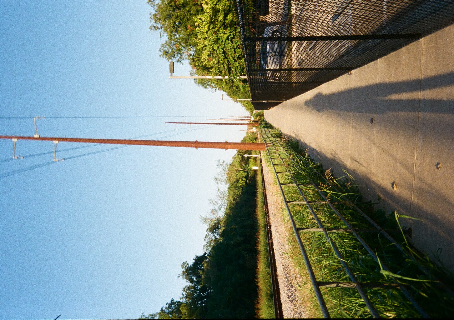 A long and straight sidewalk parallel with train tracks